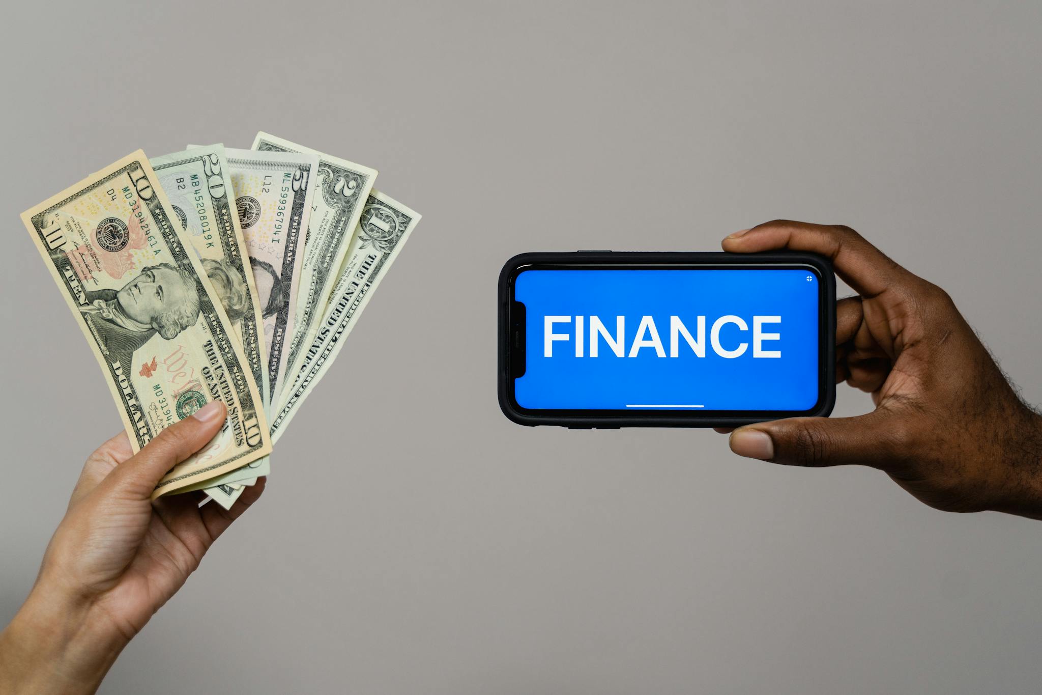 Image depicting currency and finance concept with hands holding cash and a smartphone.